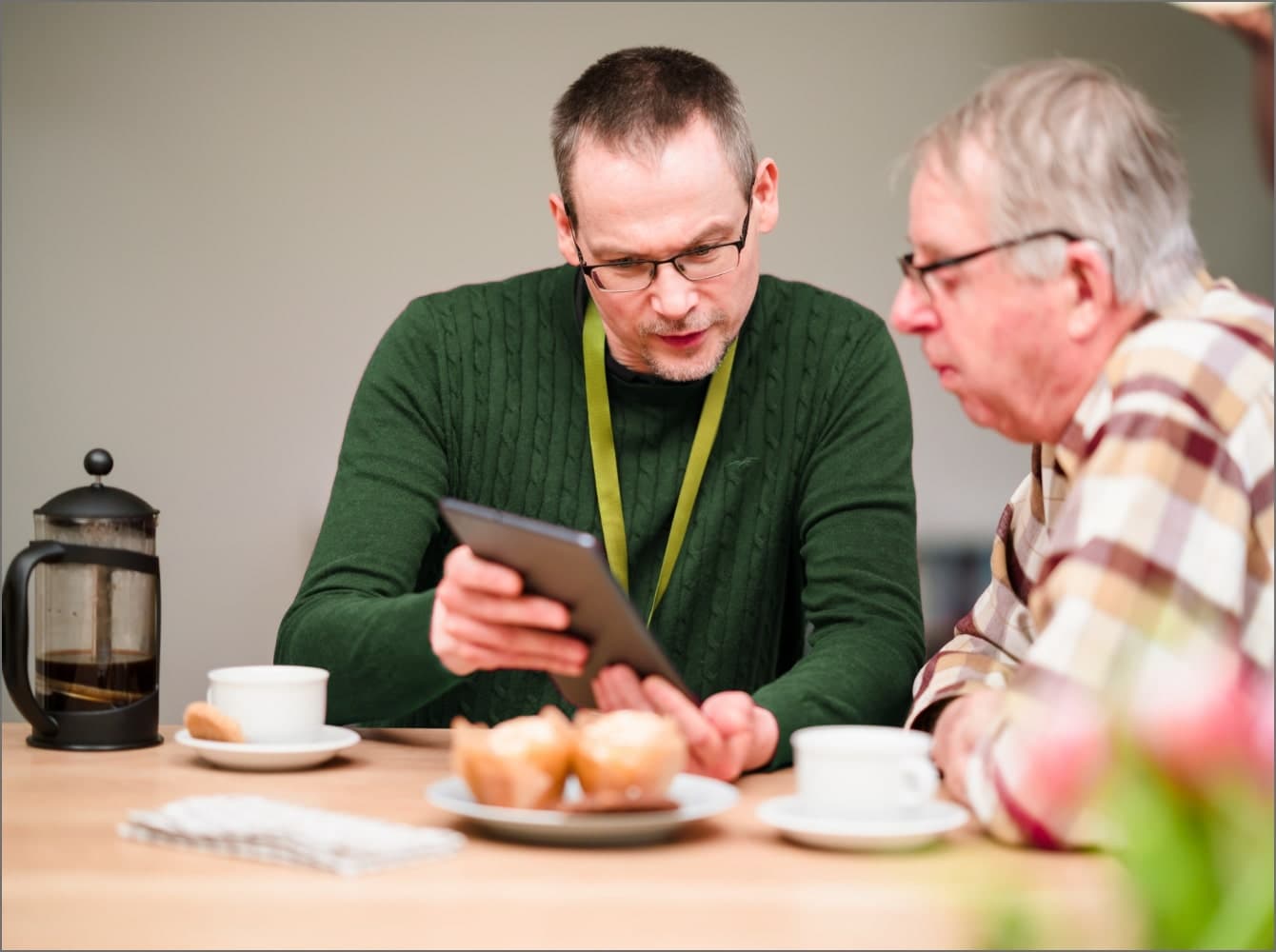 Care worker helping an elderly person select clothing in a bright room, mirror reflecting the scene in the background. - Home Instead