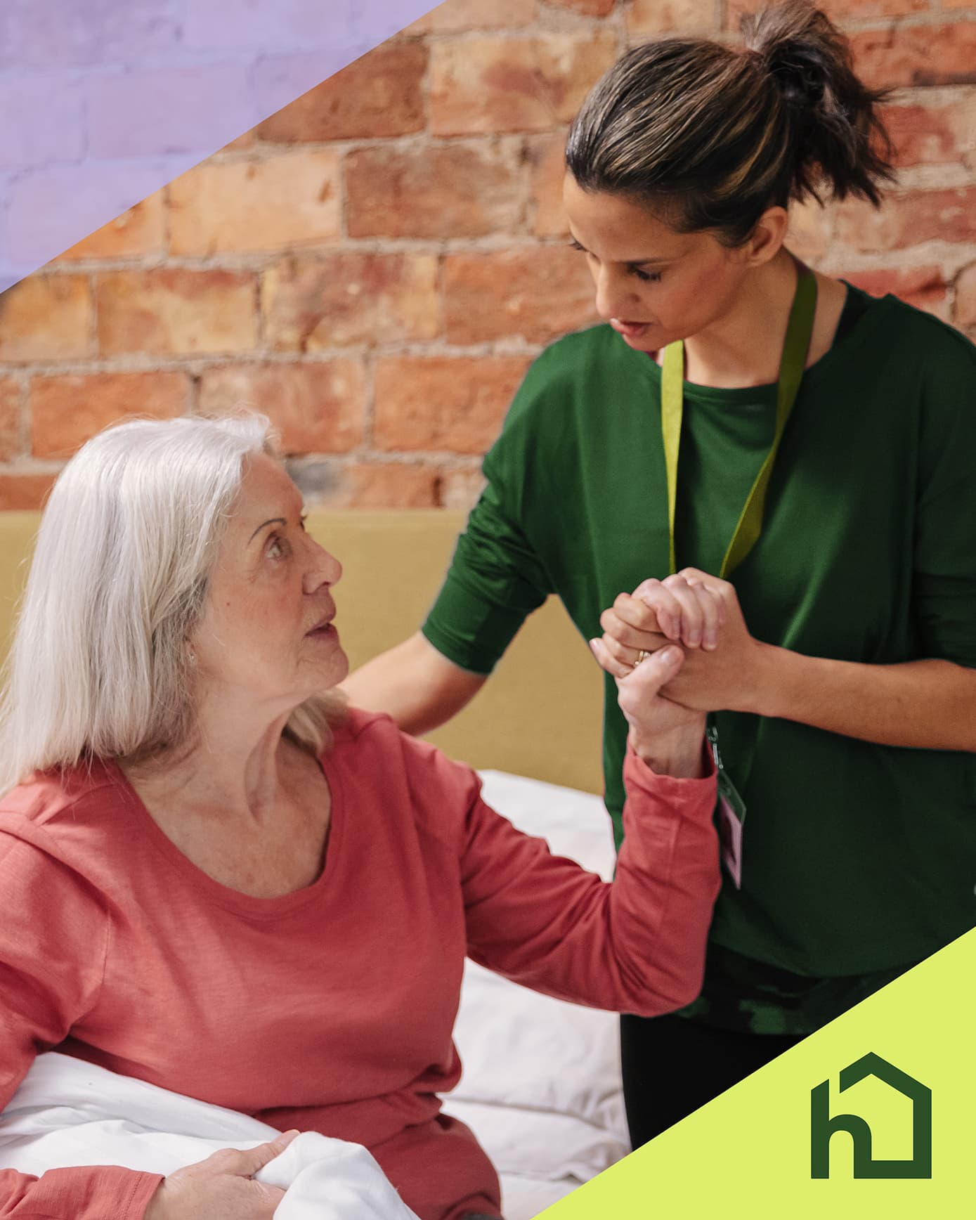 A carer supports an older woman sitting on a bed, holding her hand in a comforting gesture. - Home Instead