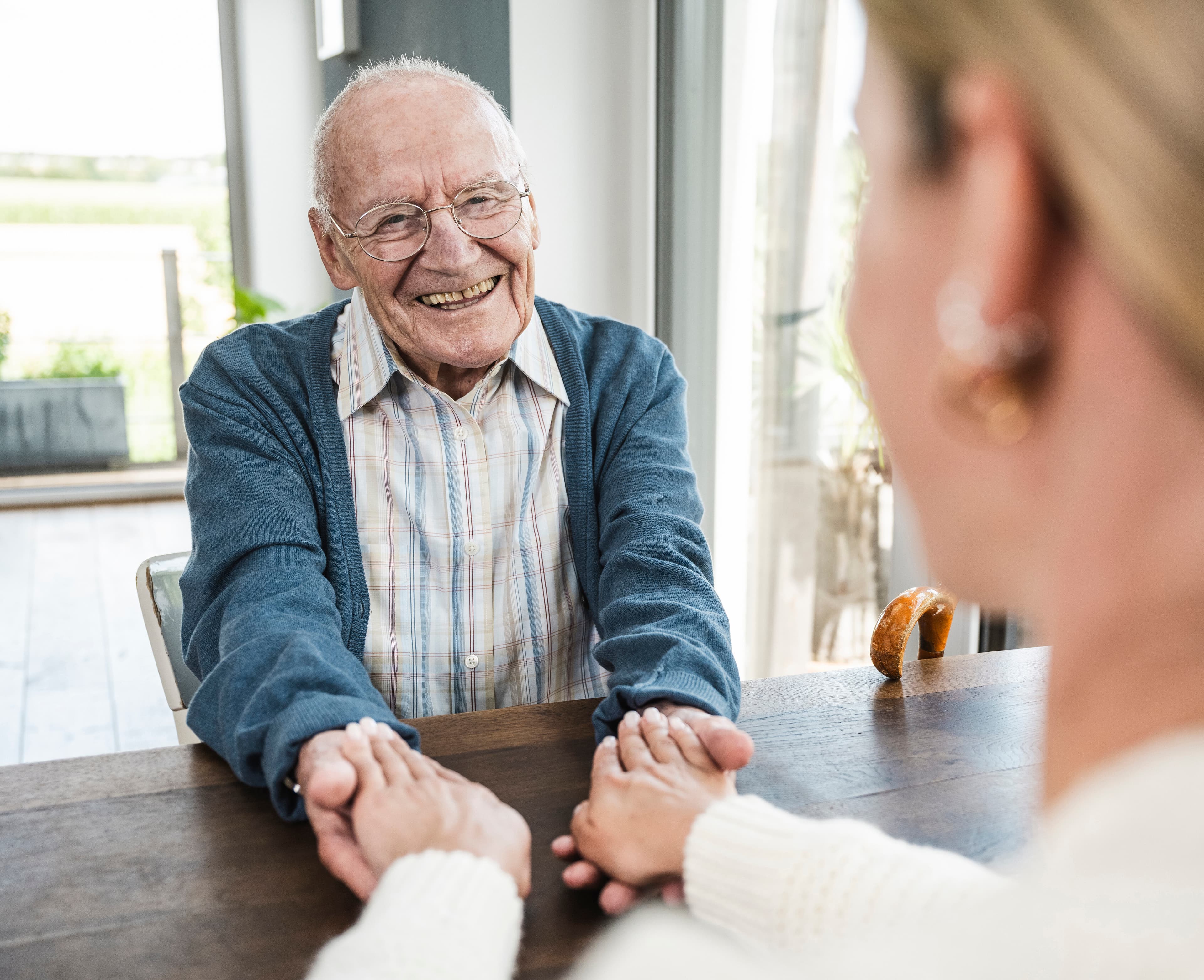 Happy senior man holding hands with daughter at home