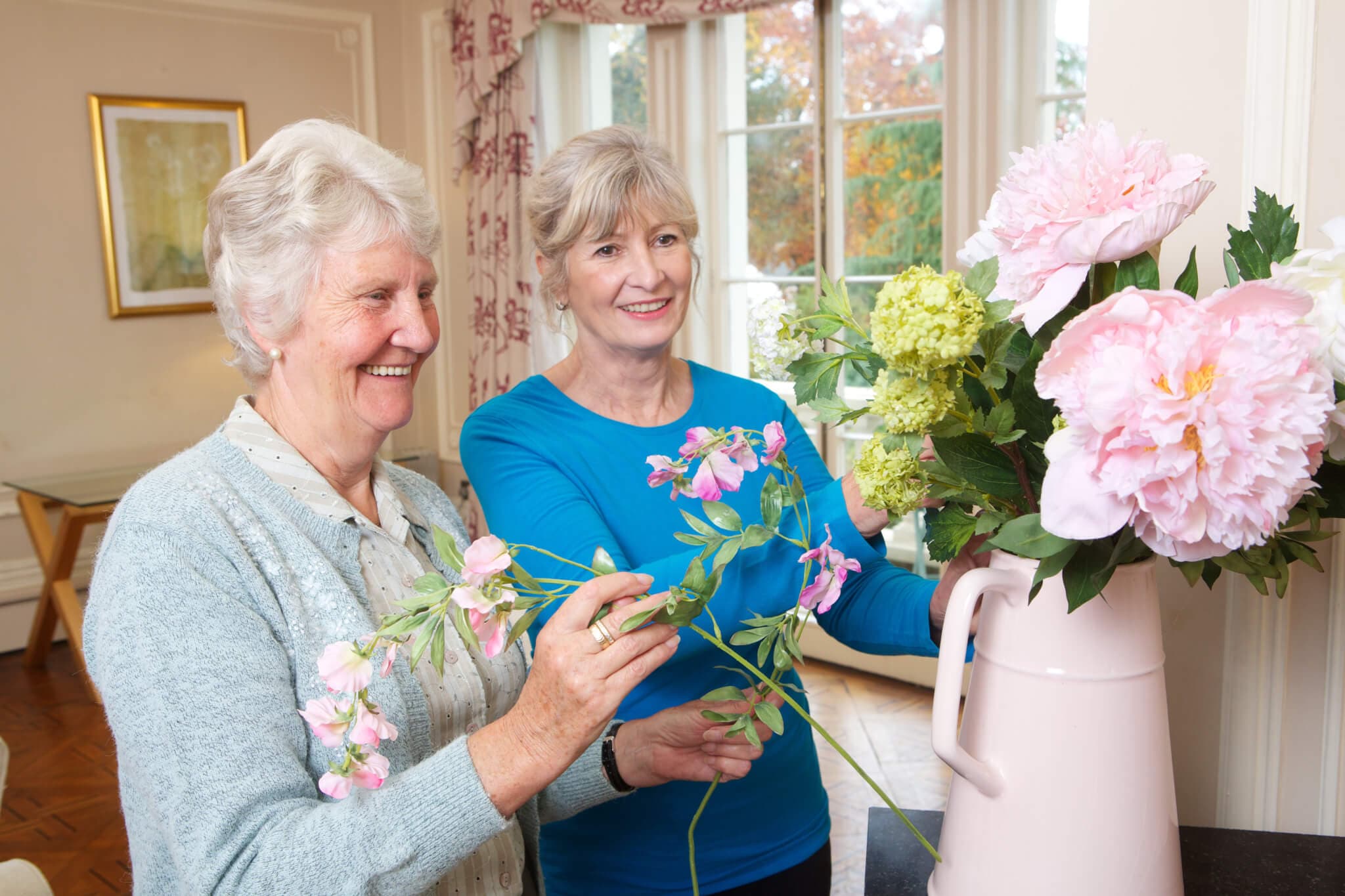 Home Instead client and Home Instead carer arrange flowers together at the clients home
