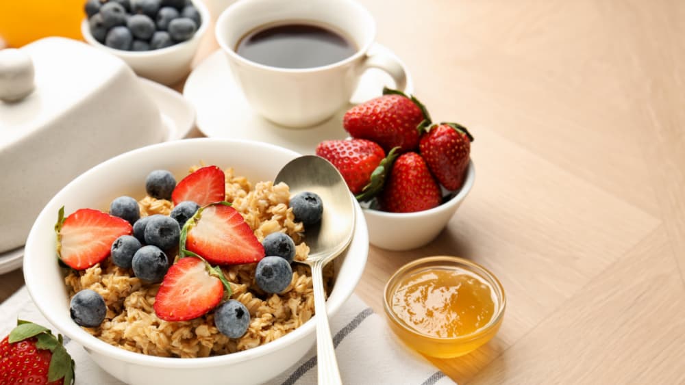 A healthy breakfast of coffee, fresh fruits such as strawberries and blueberries, yoghurt and granola - Home Instead Central Hampshire