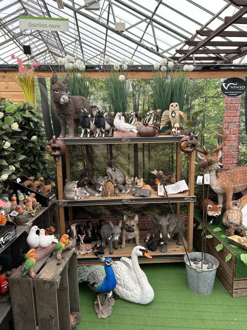 Home Instead Basingstoke picture of display of various garden animal statues, including birds, deer, rabbits, and a peacock, in a greenhouse setting at Dummer Garden Centre, near Basingstoke