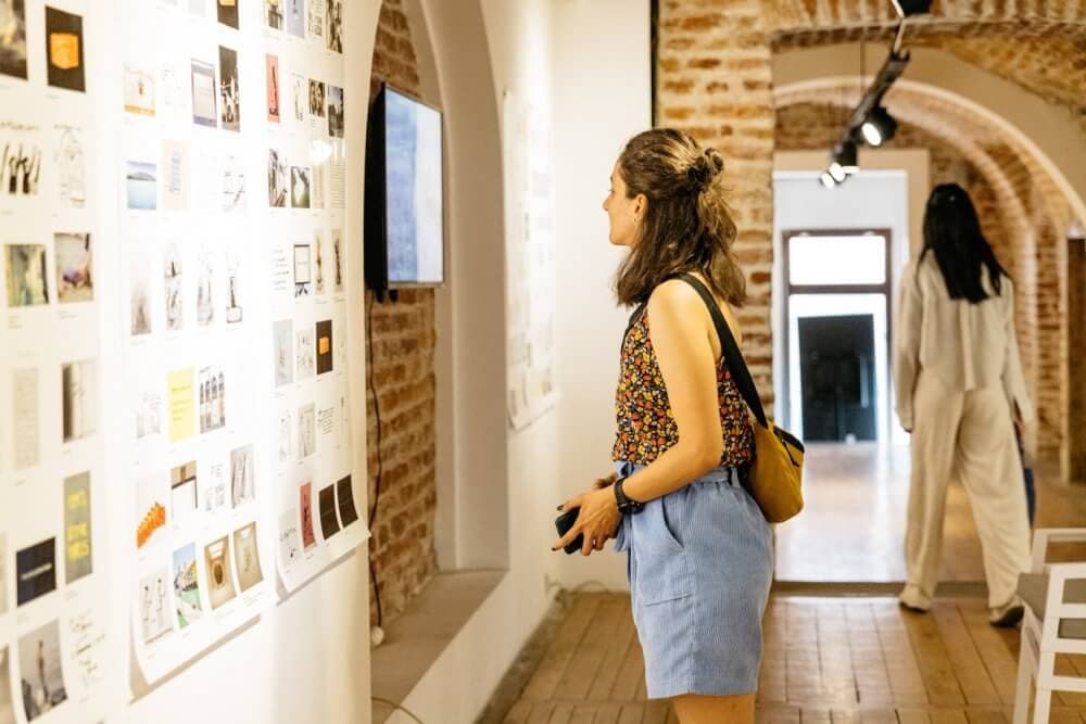 Two women viewing art in a gallery with brick walls and arched doorways. - Home Instead