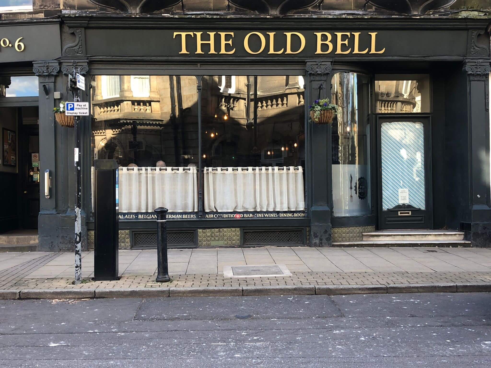 Storefront of "The Old Bell" pub with large windows and closed curtains, located on a quiet street. - Home Instead