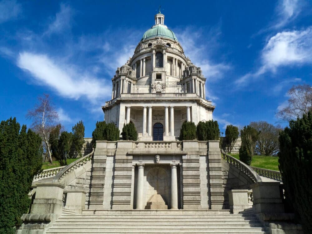 A grand, historic domed building with stairs and trees under a clear, blue sky. - Home Instead