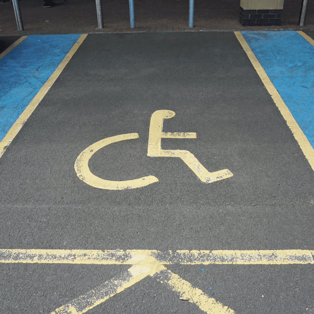 A designated handicap parking space with blue borders and a yellow wheelchair symbol painted on the ground. - Home Instead