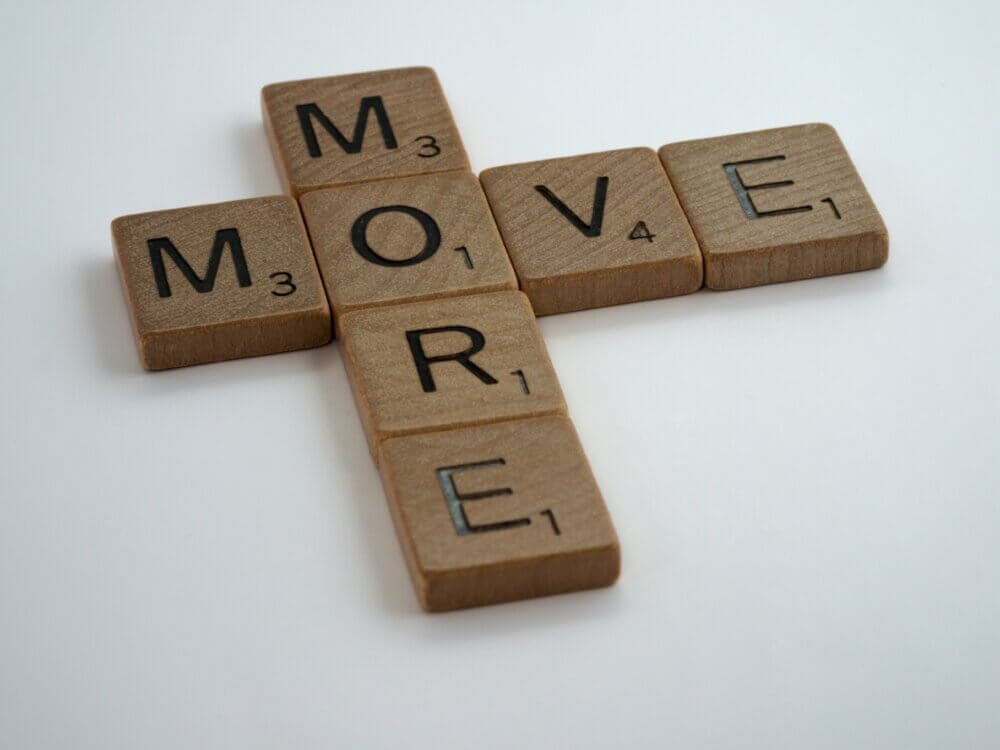 Scrabble tiles arranged to form the words "MORE" and "MOVE" in a cross pattern on a white background. - Home Instead