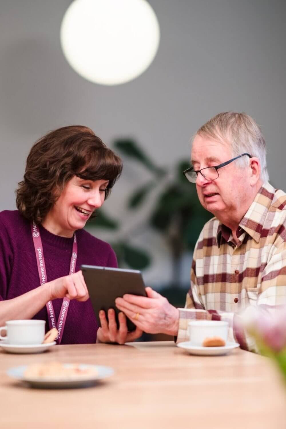 A man and woman looking at a tablet. - Home Instead