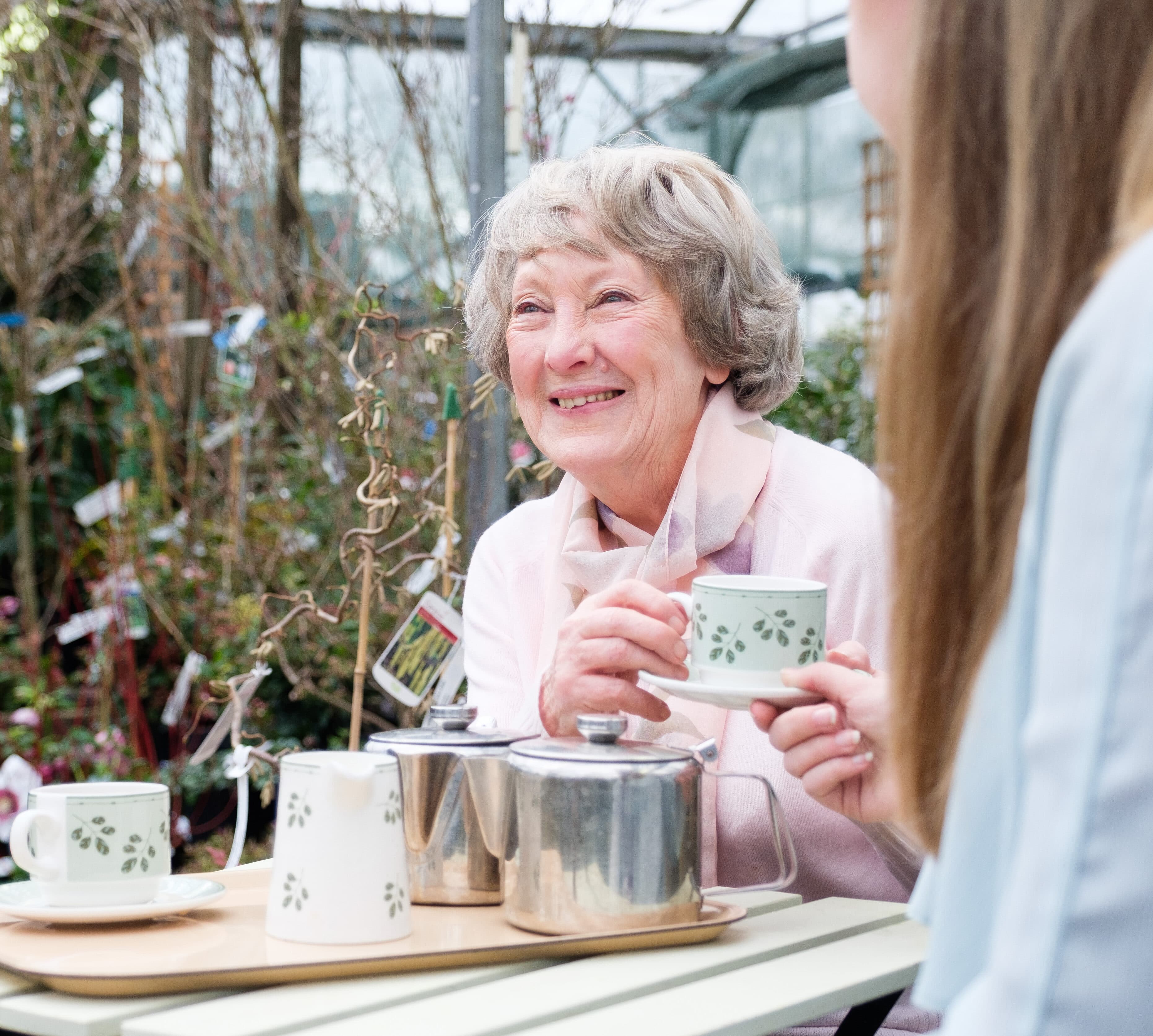 Home Instead live-in care client enjoying a cup of tea in the garden with her Home Instead live-in carer