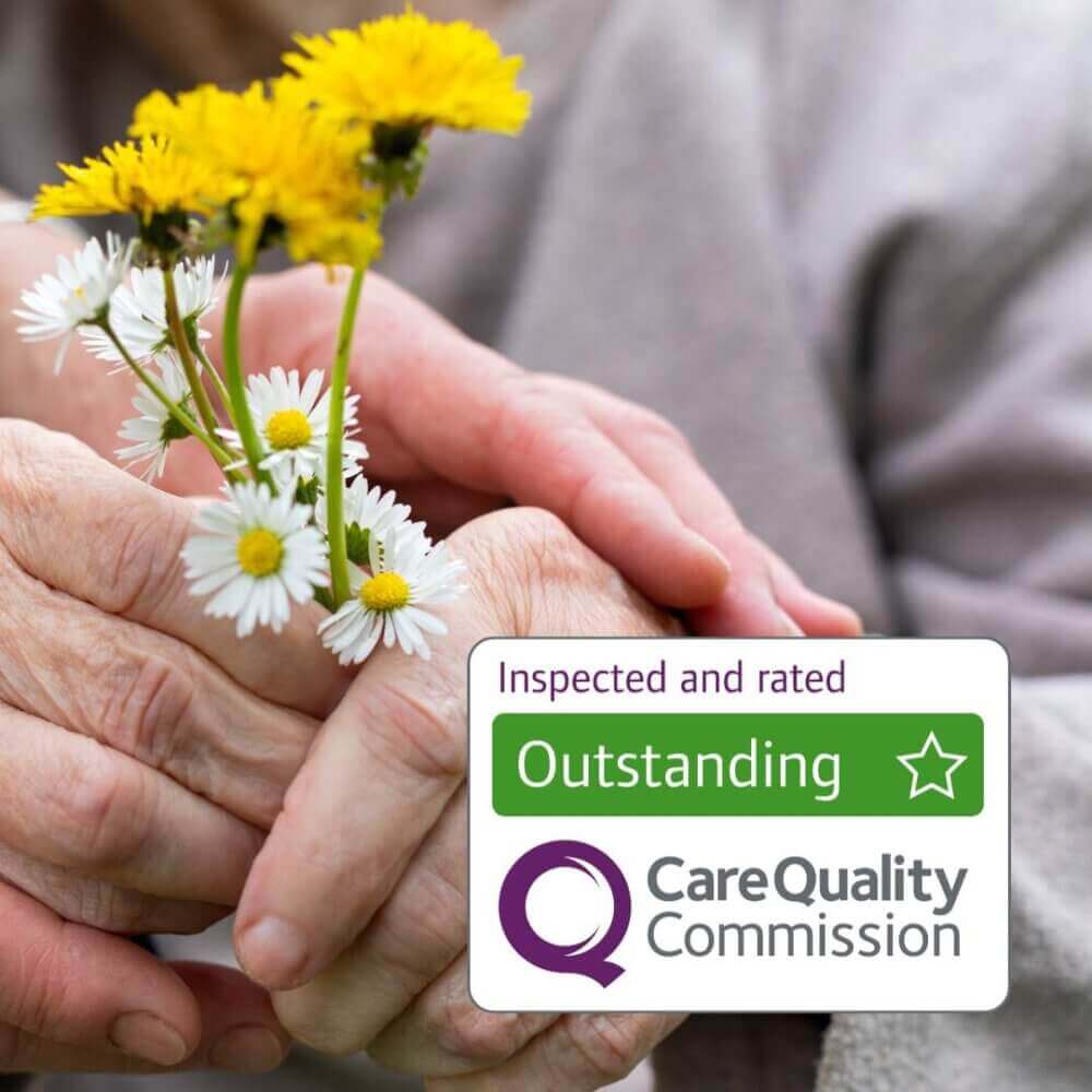 An elderly hand holding flowers next to a Care Quality Commission 'Outstanding' rating sign. - Home Instead