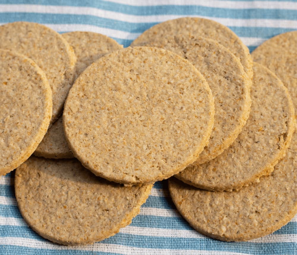 Round oatmeal crackers stacked on a blue and white striped cloth. - Home Instead