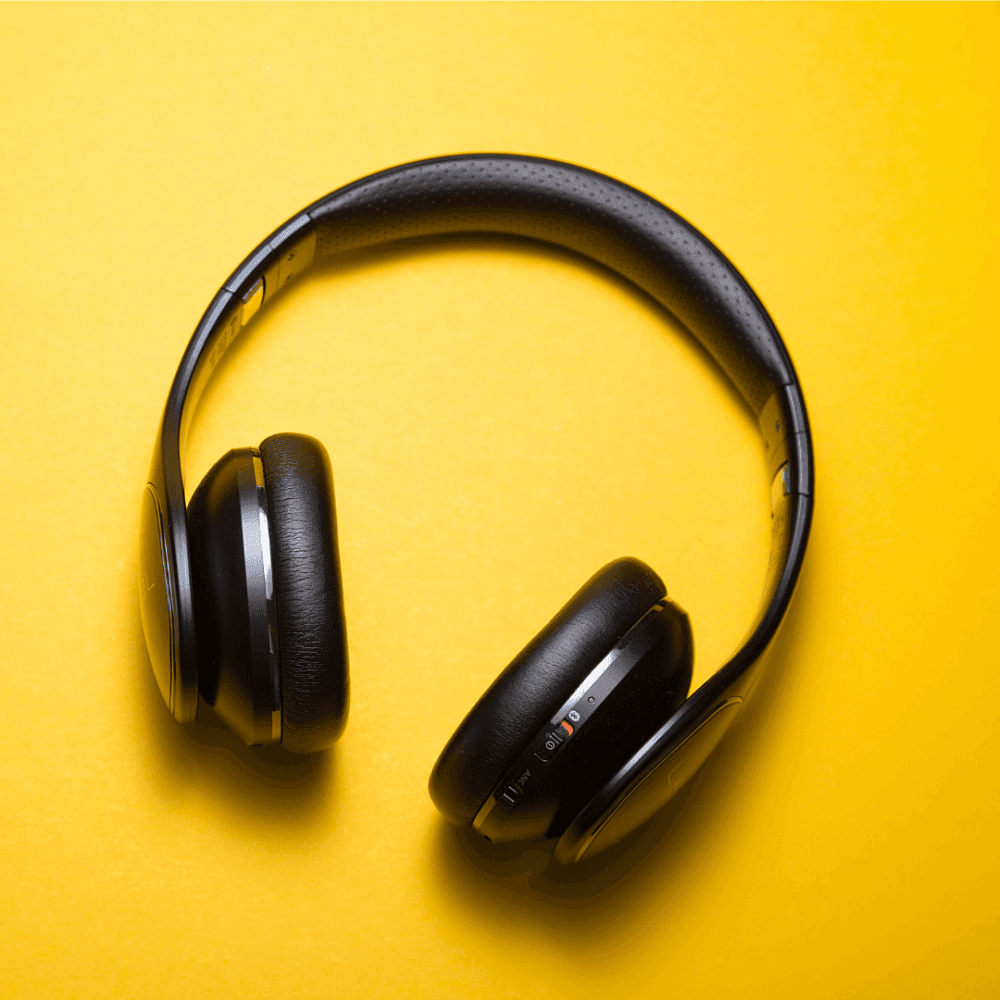 Black over-ear headphones placed against a bright yellow background. - Home Instead