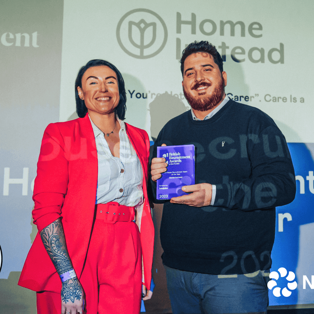 The team standing and smiling, one holding their recruitment award.