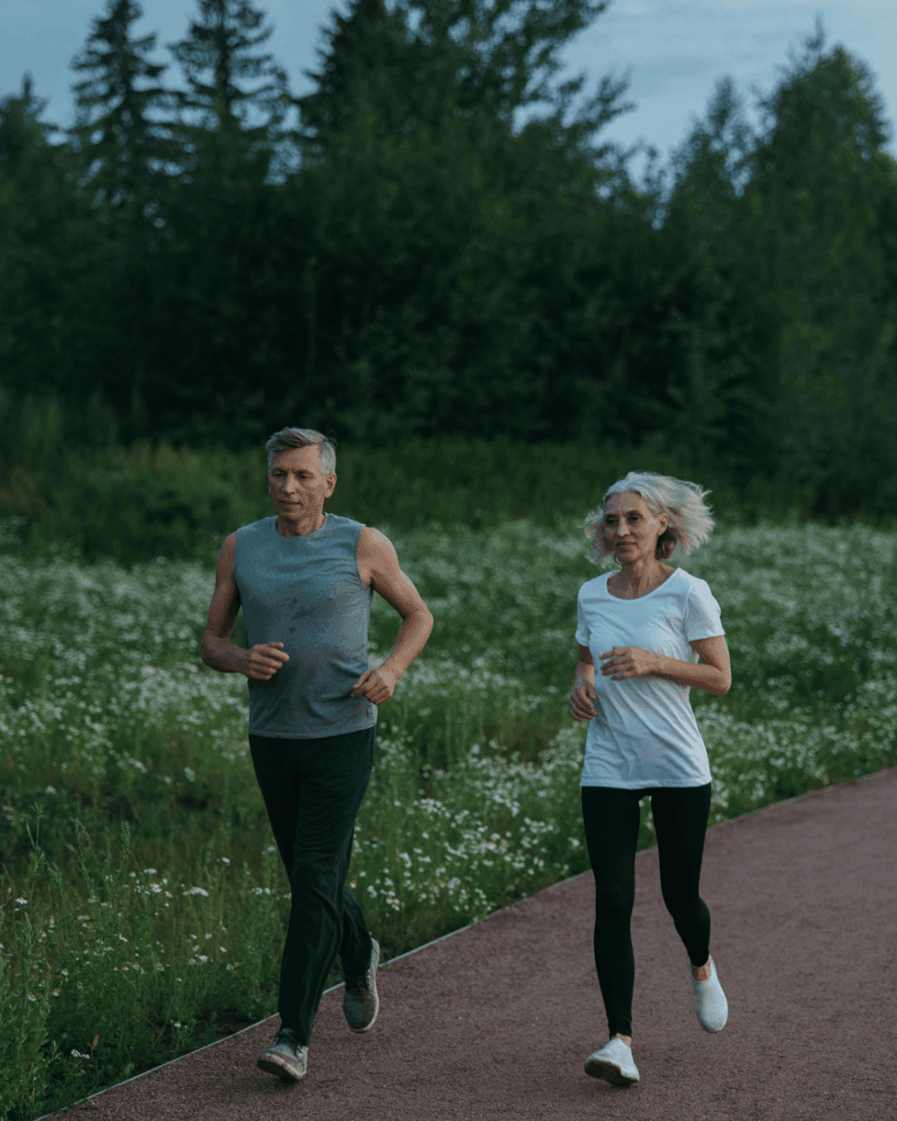 Older man and woman jogging outdoors in the countryside at dusk