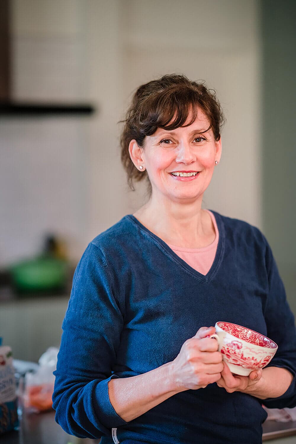woman with a cup of tea in kitchen looking in the camera