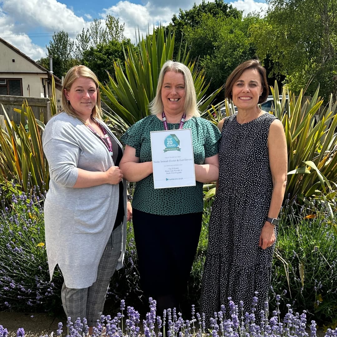 Rhema, Anna and Vanessa stand in the garden holding the homecare award.