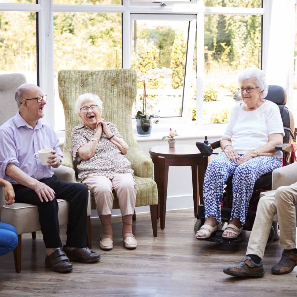 group of seniors sitting together in a communal room within their assisted living facility