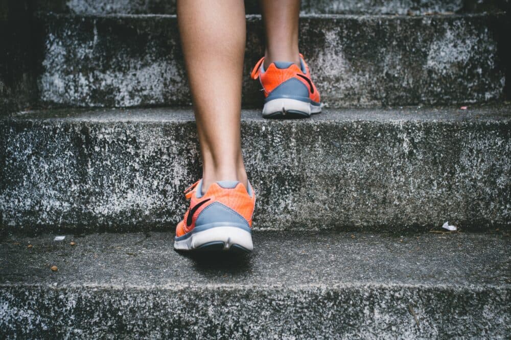 Person wearing orange sneakers walking up concrete stairs. - Home Instead