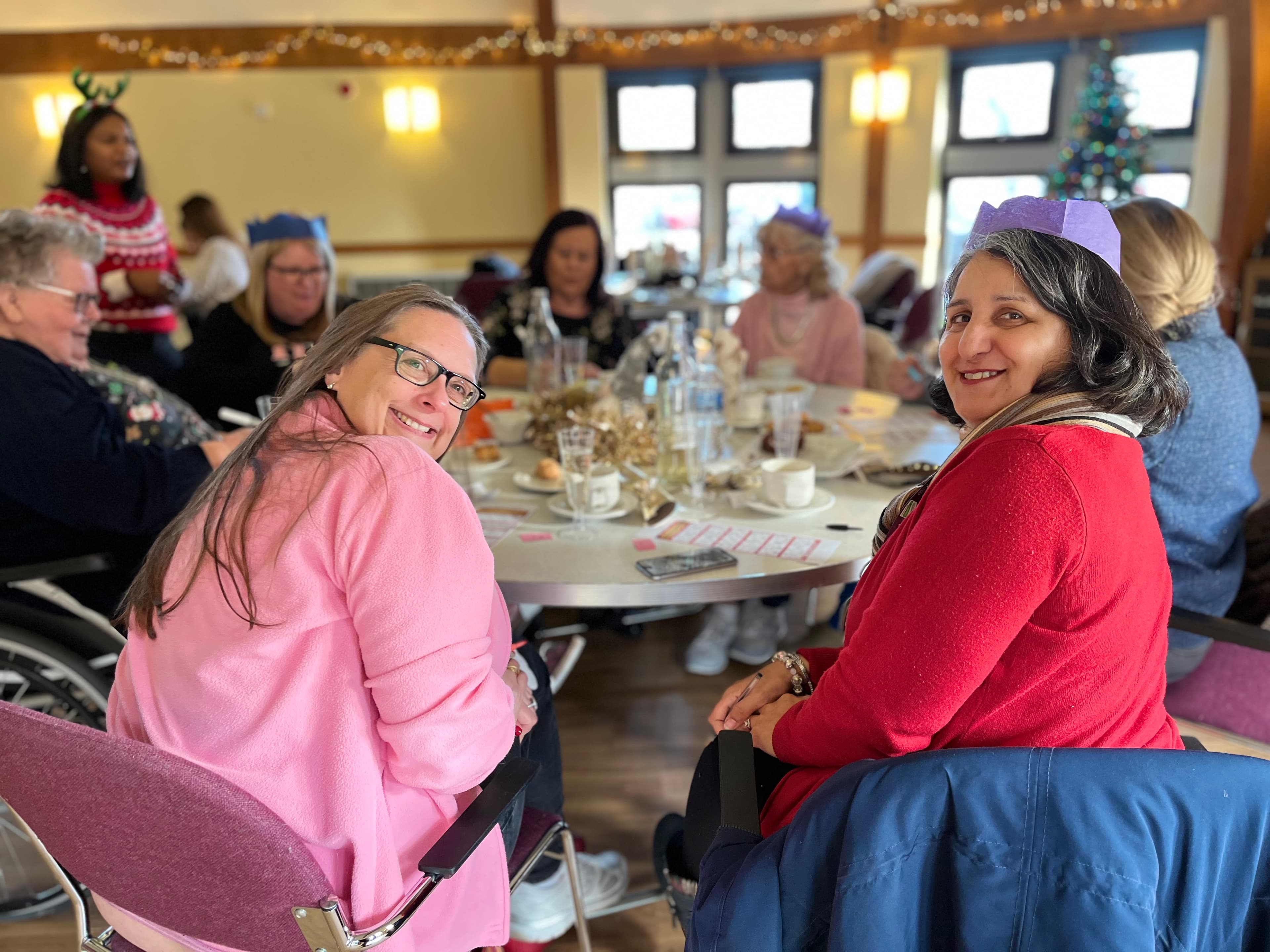 Christmas party with clients and care professionals smiling and enjoy some food.