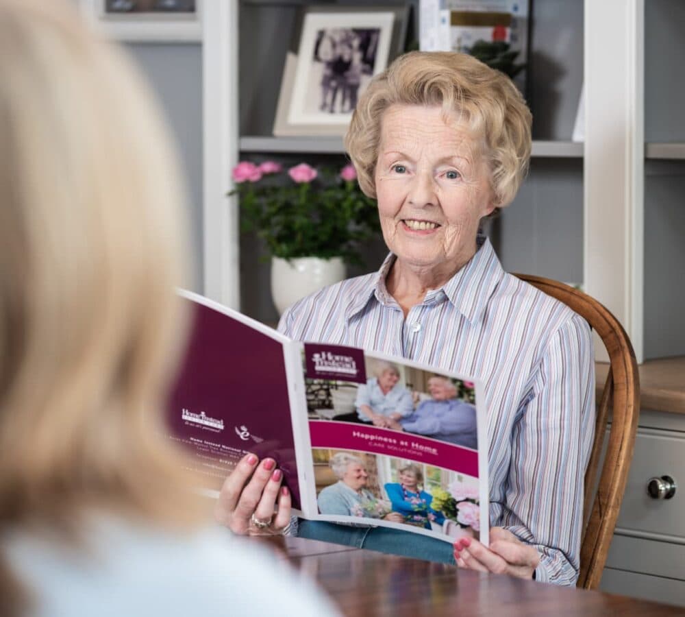 Senior woman with short hair holding Home Instead brochure