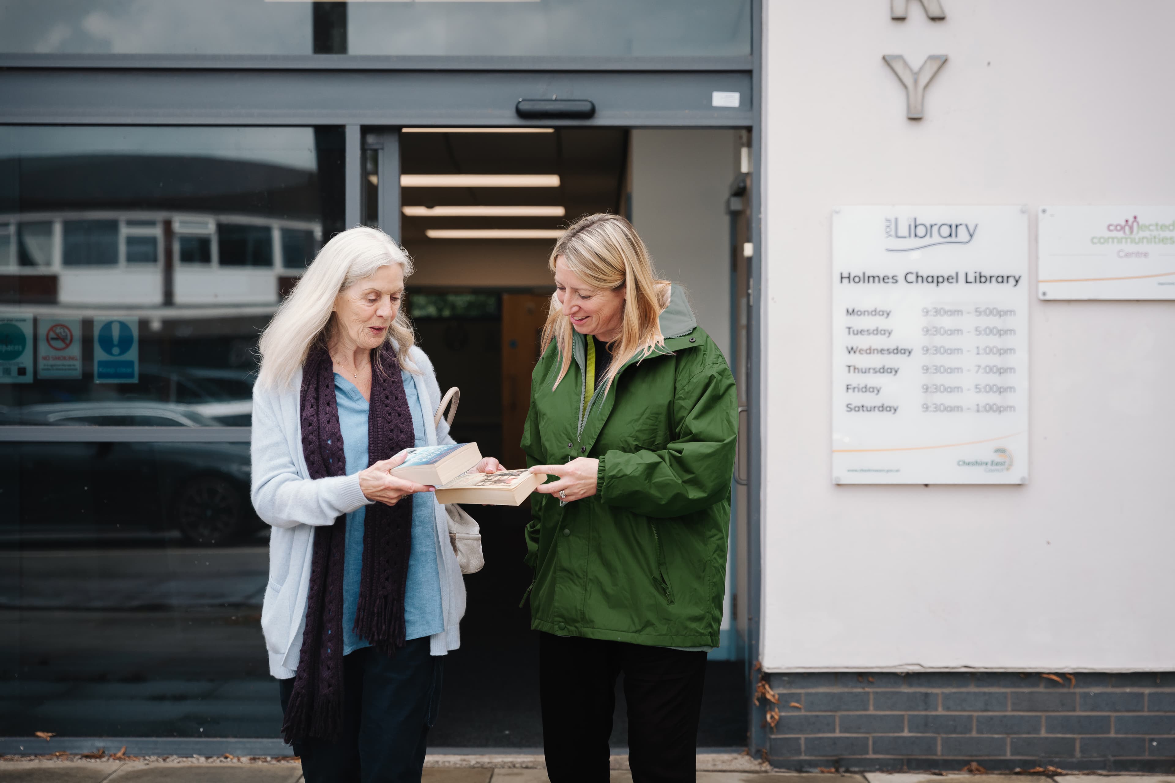 Care pro and client coming out from a library
