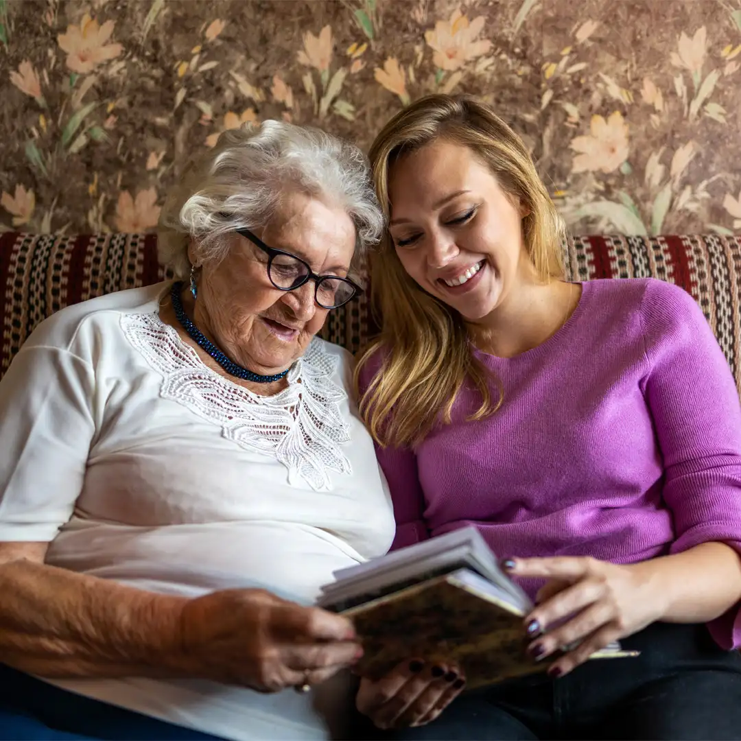Care professional reminiscing with client looking through photo albums