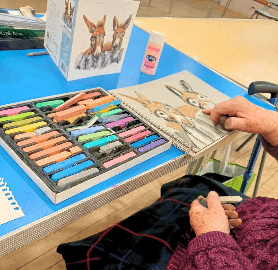 A woman in an art class painting a picture of two donkeys