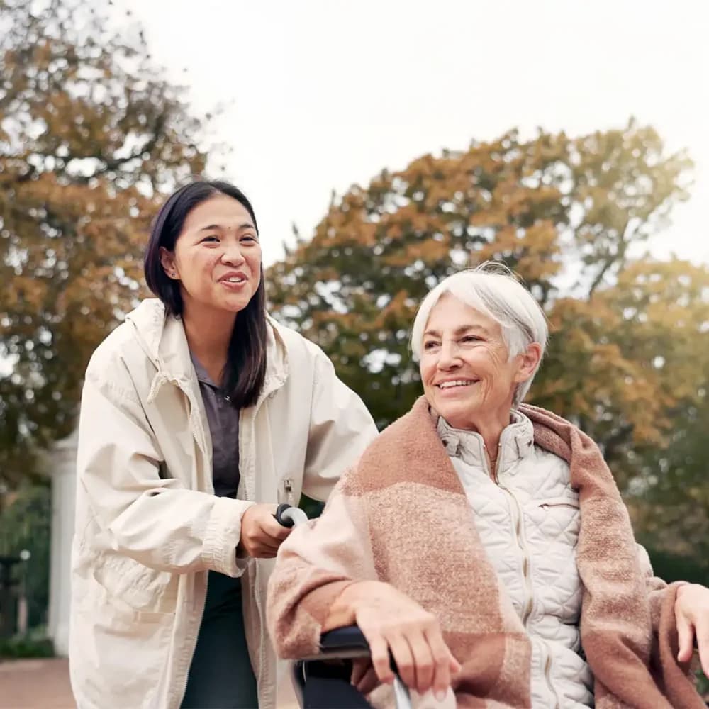 older female care professional pushing her client in a wheelchair