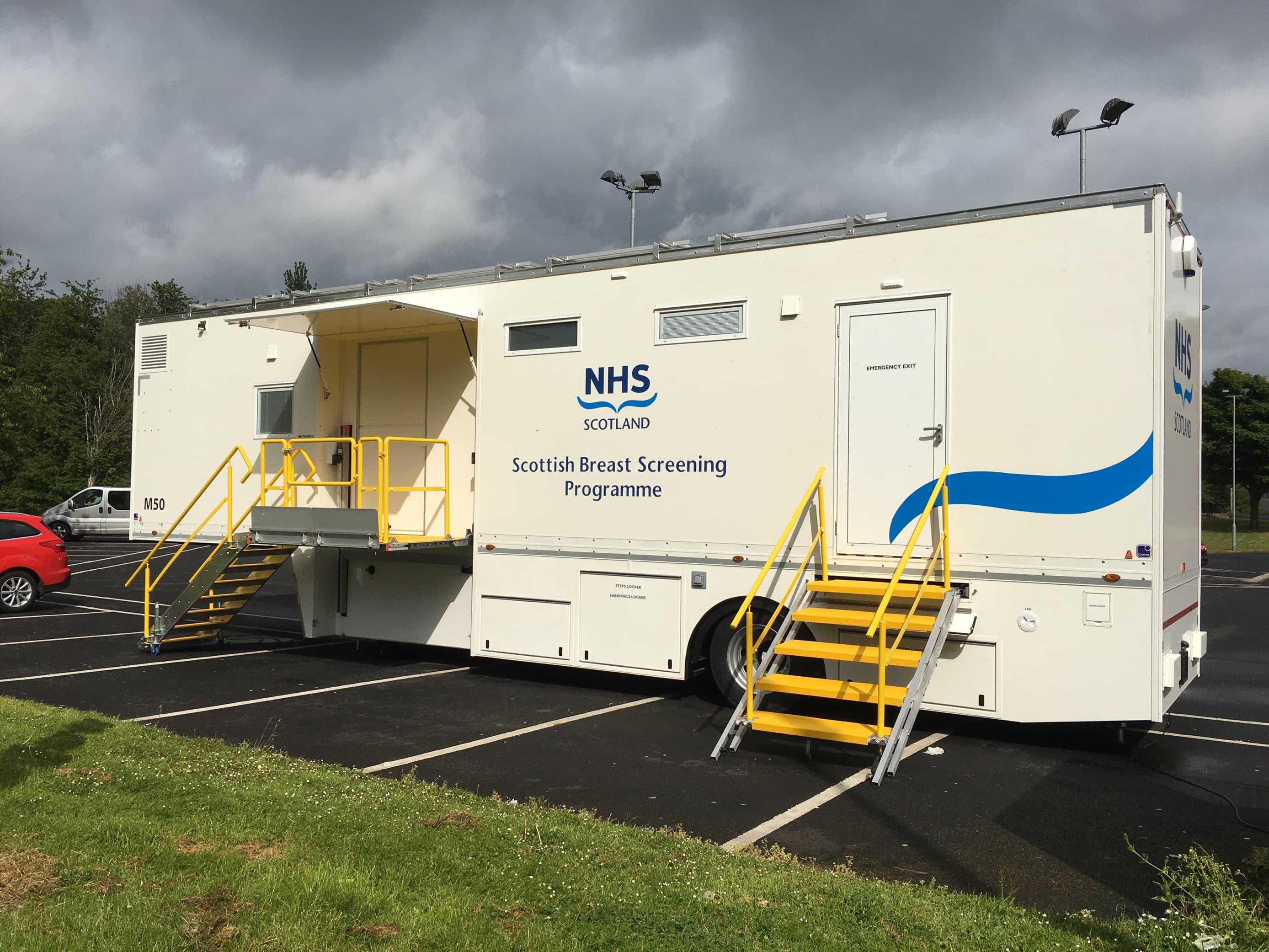 Mobile NHS Scotland breast screening unit parked in a lot, with yellow stairs leading to its entrances. - Home Instead