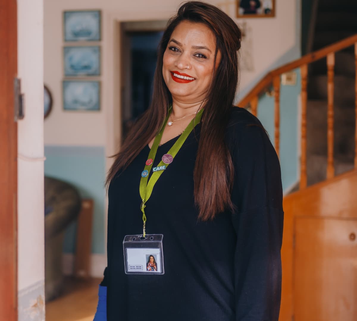 An older female adult wiht long black hair happy and smiling while standing inside the house