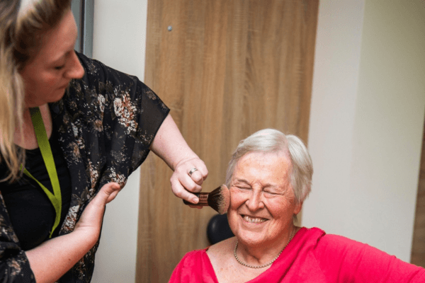 Live-in Care Professional applying make up to her smiling client