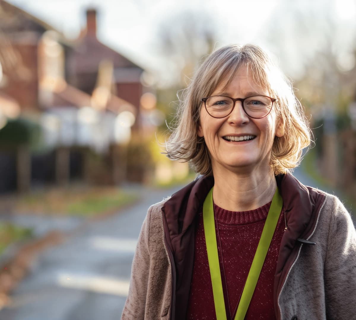 A woman with short blonde hair and wearing eyeglasses standing on the road