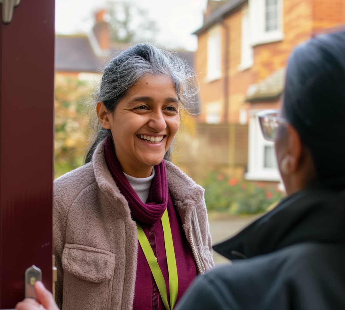 A female with grey hair happy and smiling while being greeted at the door