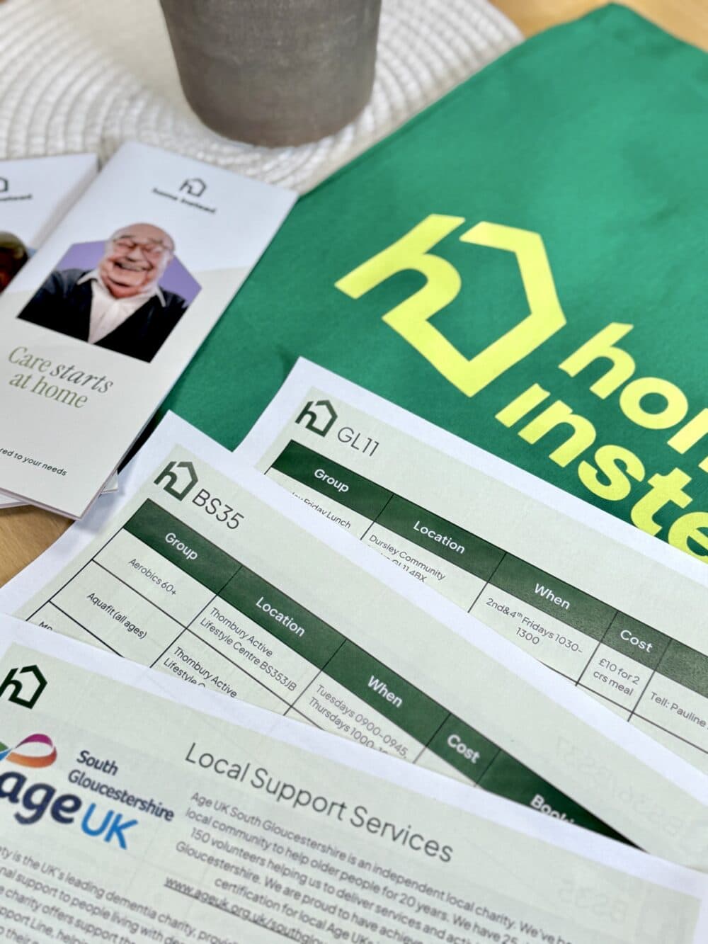 Home Instead brochures, lists of support services, and a green Home Instead bag on a table. - Home Instead