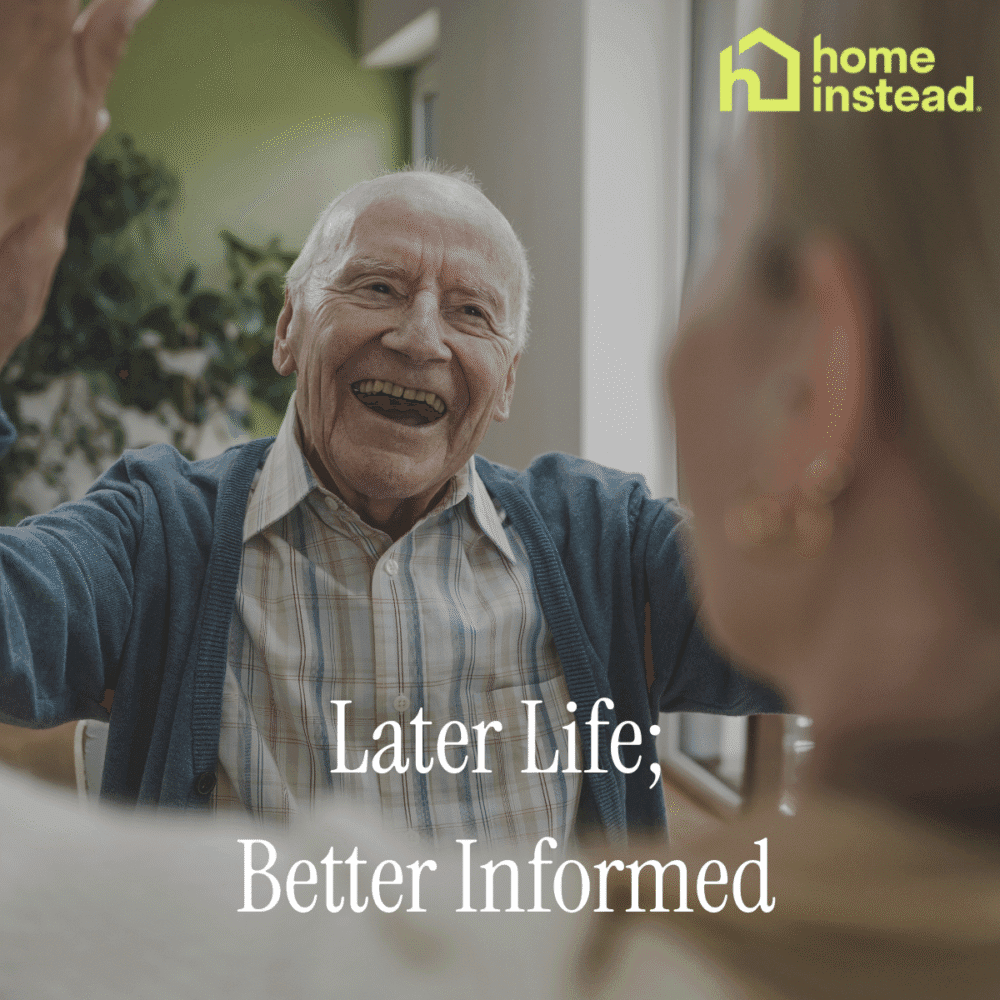 Smiling elderly man talking to others indoors, with “Later Life; Better Informed” and Home Instead logo. - Home Instead