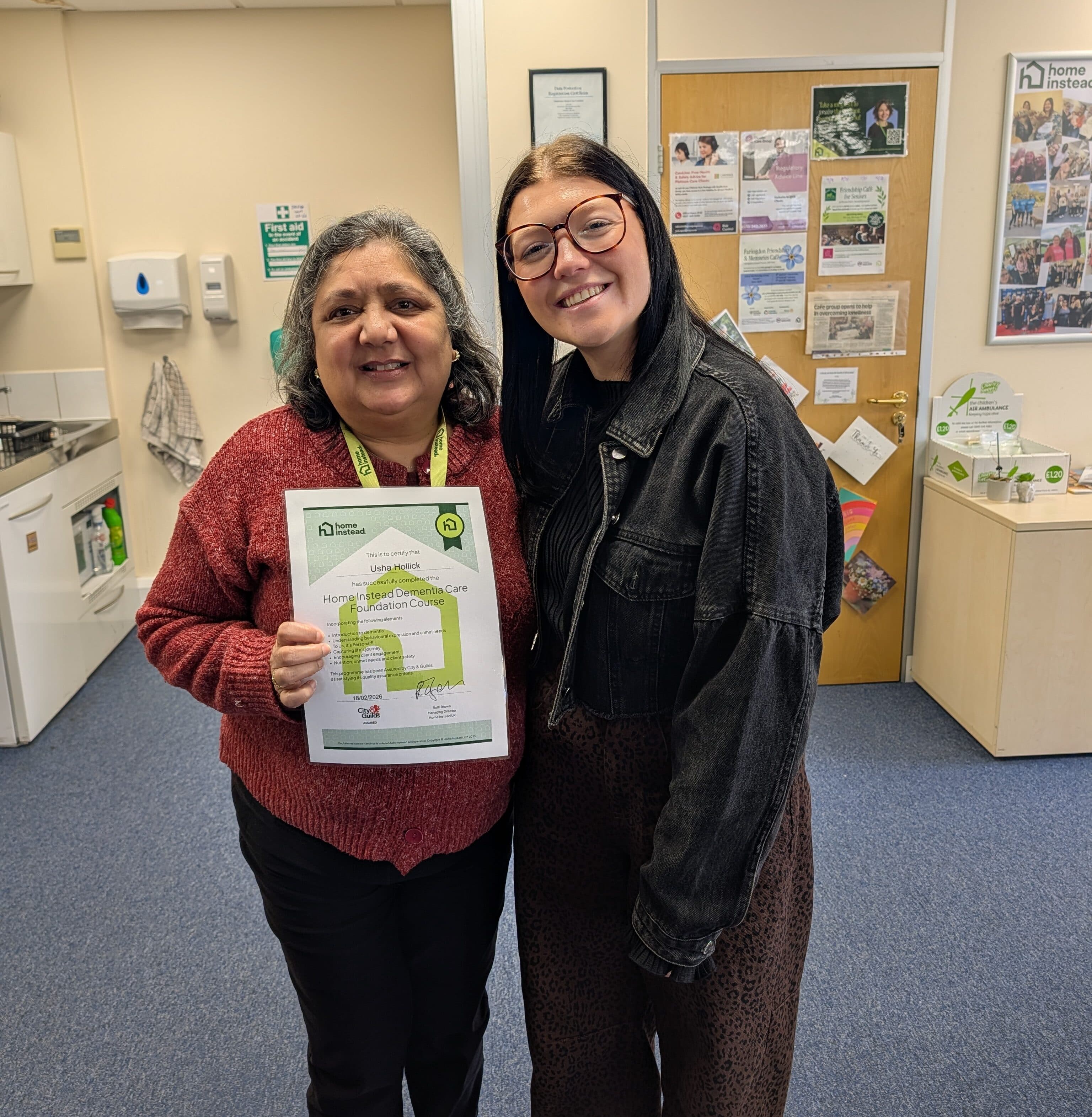 Two women smile together indoors; one holds a framed certificate for home improvement. - Home Instead