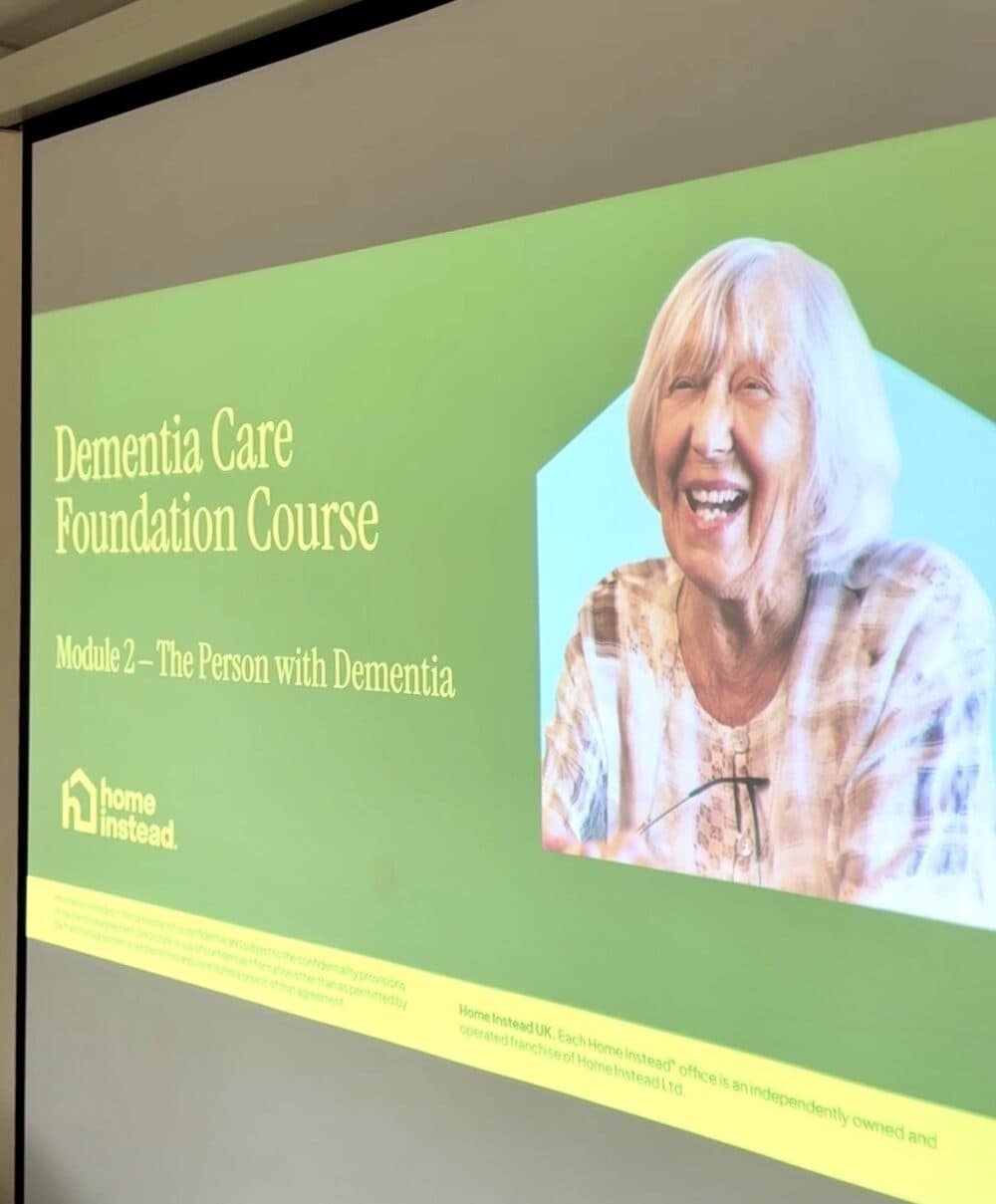 Slide for "Dementia Care Foundation Course, Module 2" with a smiling elderly woman on the right side. - Home Instead