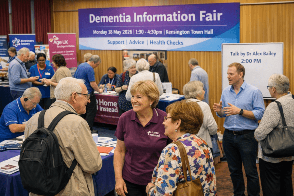 People interacting at a Dementia Information Fair with support stalls and informational signs in a hall. - Home Instead