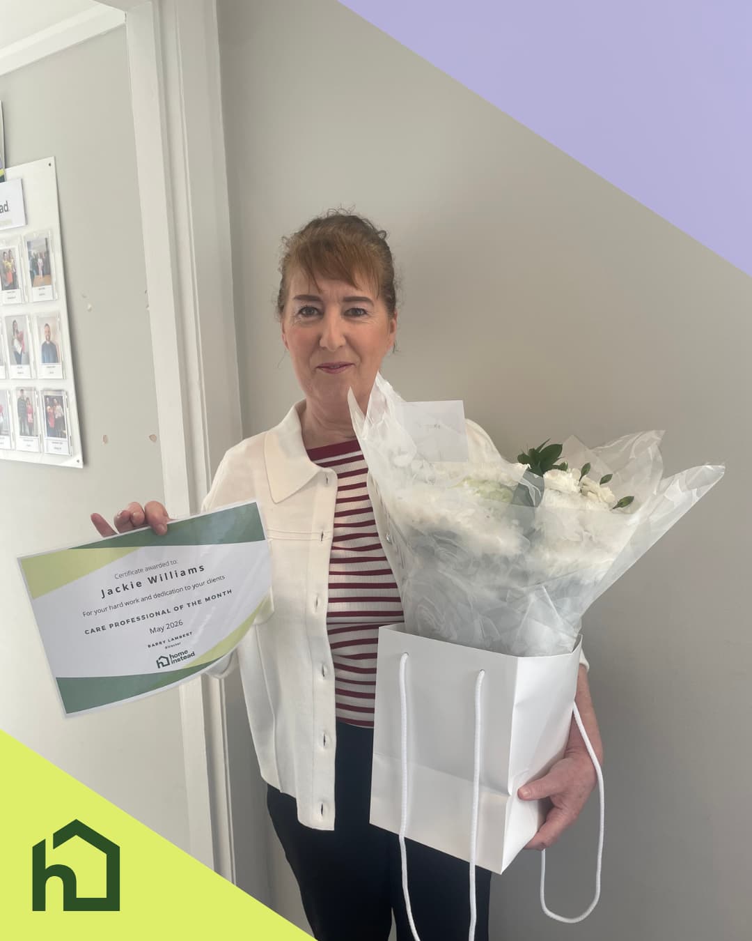 A woman holding flowers and a certificate stands smiling in an office, with a green house icon in the corner. - Home Instead