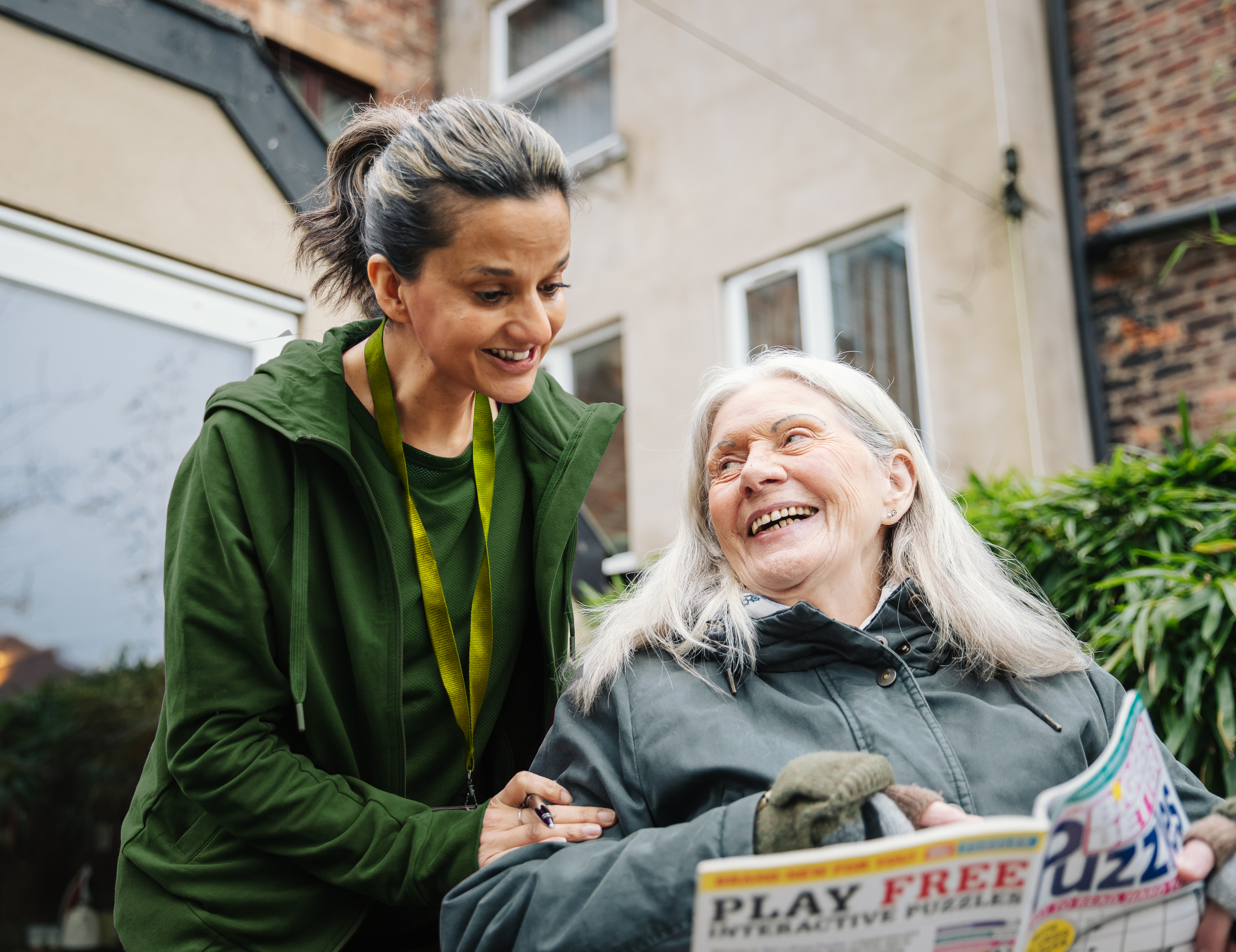 A female carer helping an elderly woman do a puzzle outside - Home Instead